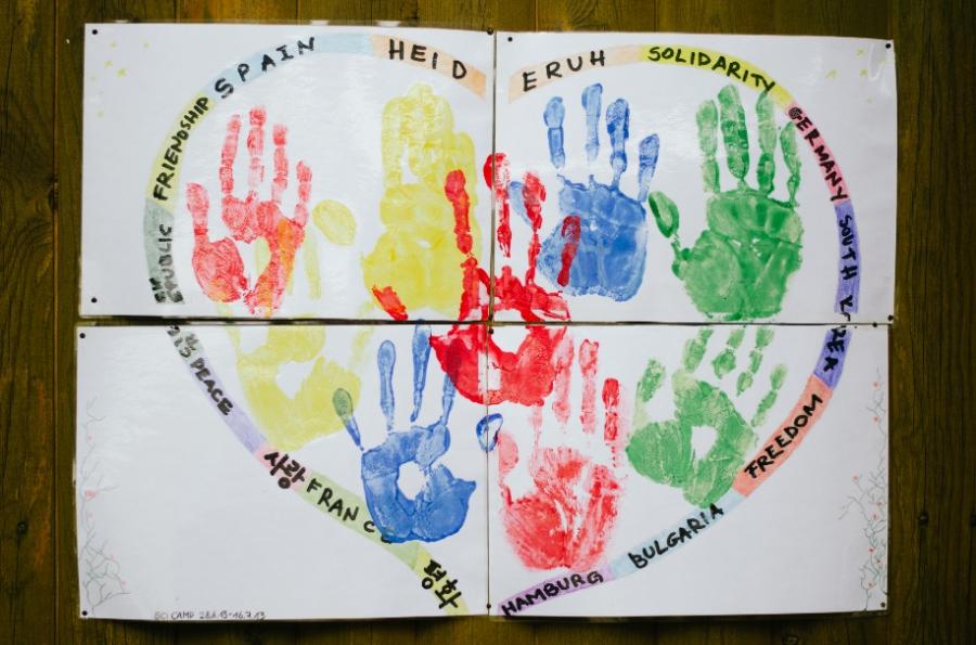 Gestalteter Text auf einem Herz mit farbigen Händeabdrücken